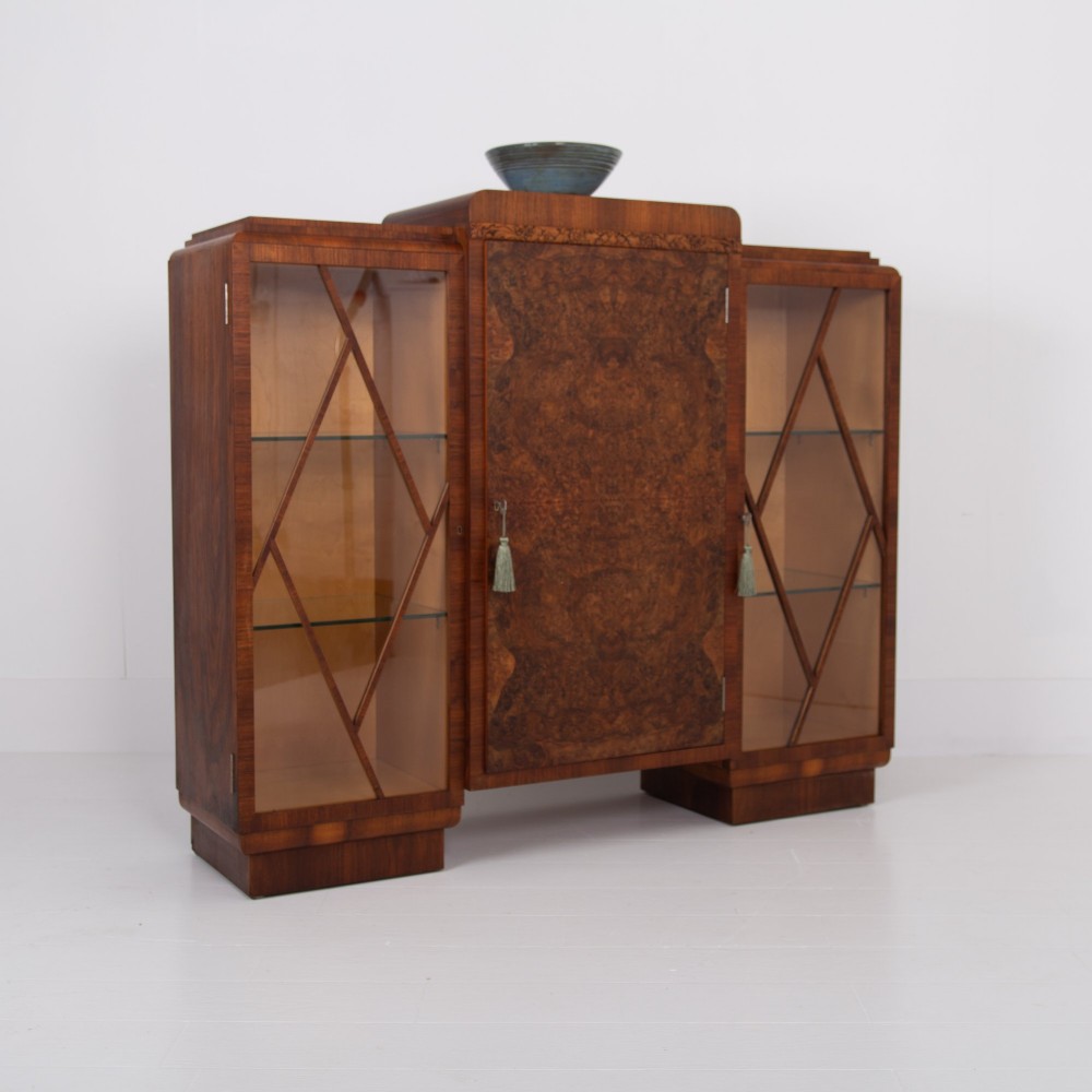 An Art Deco walnut display cabinet featuring a central burr walnut door flanked by two glazed doors with geometric diamond glazing bars. View XV
