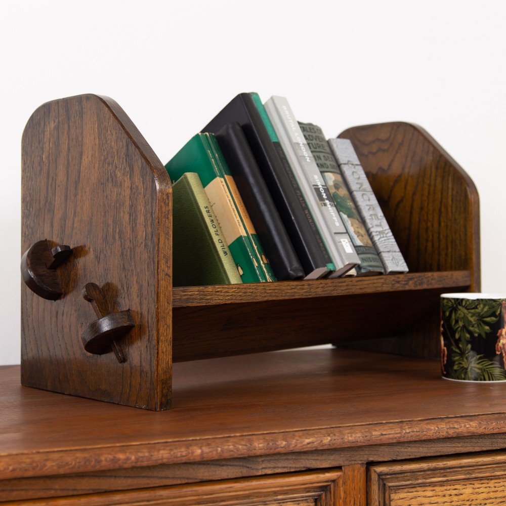 An English Arts and Crafts medium brown oak book trough featuring angled shelf panels and exposed wedge peg joinery. View II
