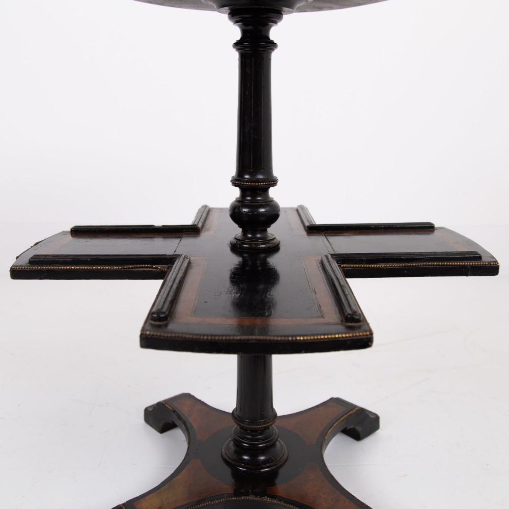 A Victorian ebonised side table featuring a circular top inlaid with amboyna wood, a central turned column, a lower cruciform tier, and a four-point flared base. View IV