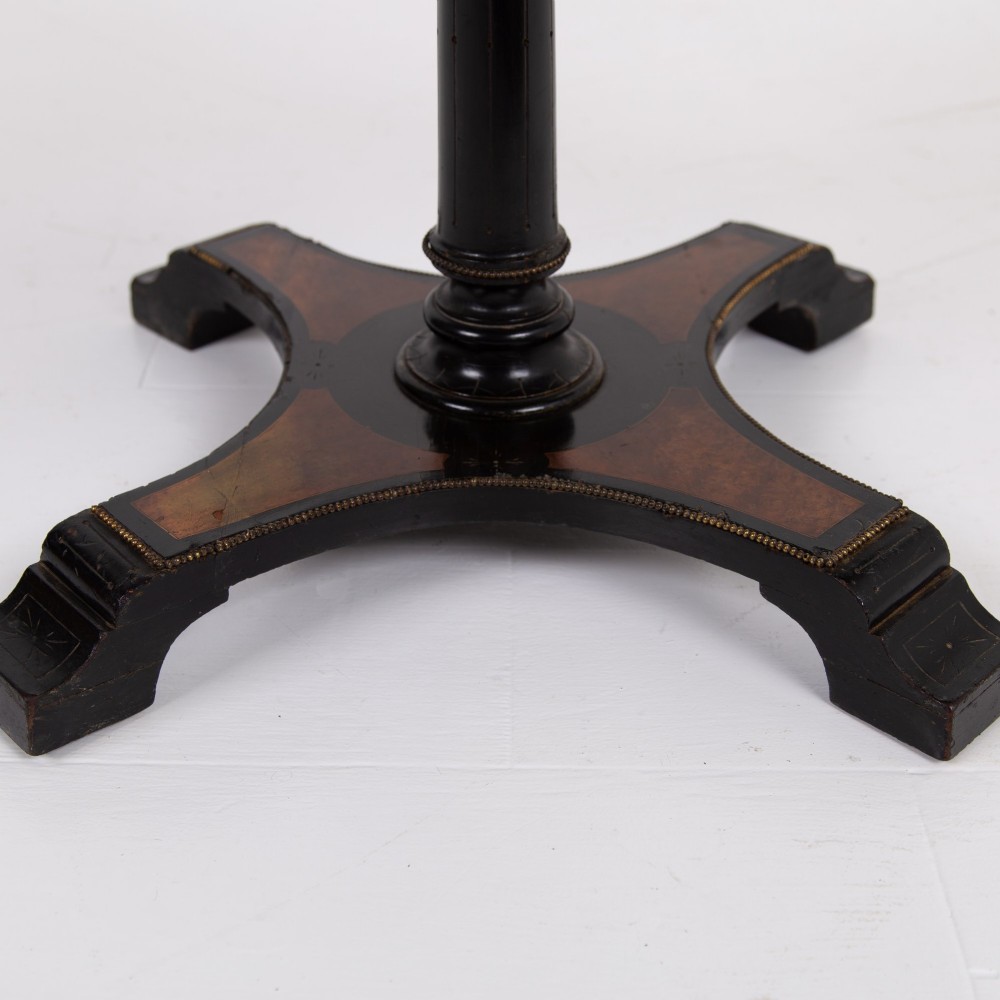 A Victorian ebonised side table featuring a circular top inlaid with amboyna wood, a central turned column, a lower cruciform tier, and a four-point flared base. View VI