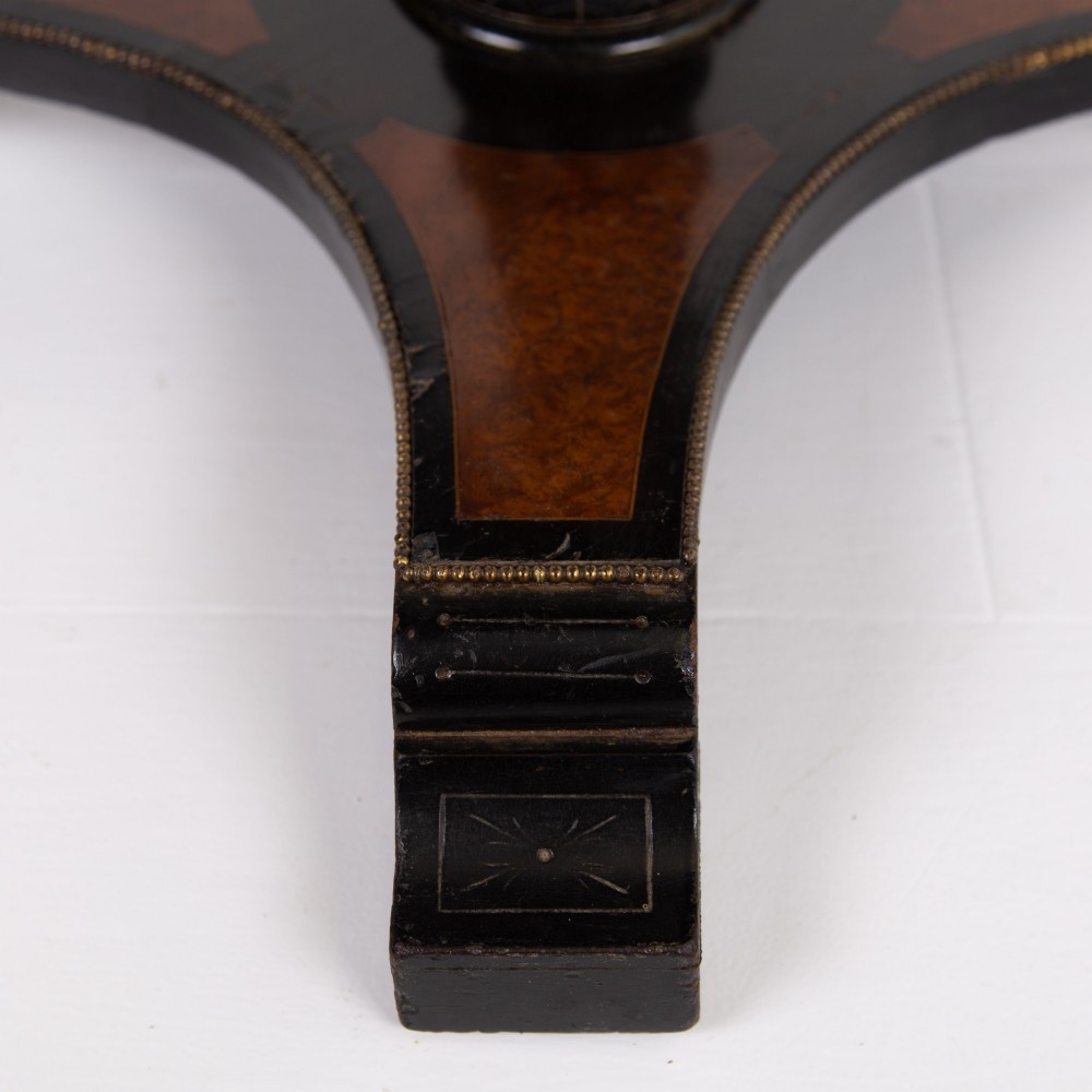 A Victorian ebonised side table featuring a circular top inlaid with amboyna wood, a central turned column, a lower cruciform tier, and a four-point flared base. View VIII