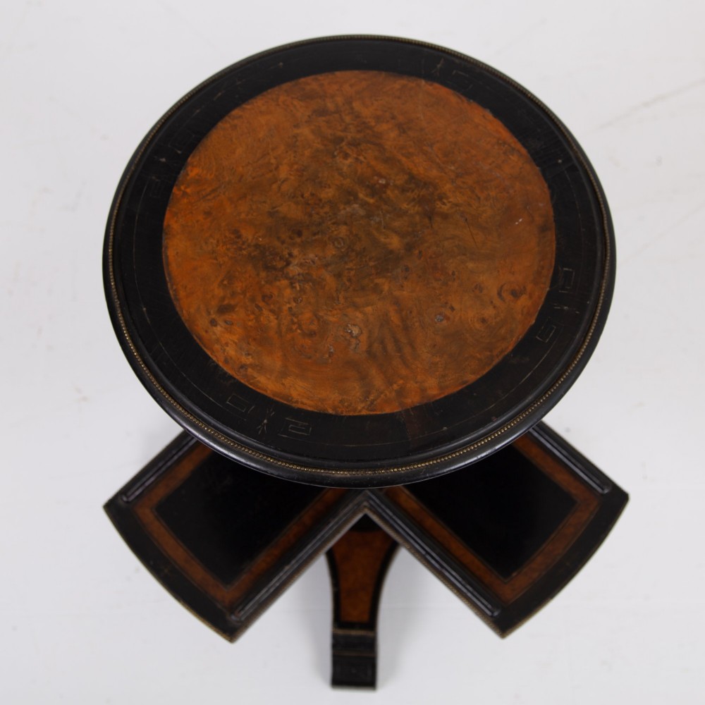 A Victorian ebonised side table featuring a circular top inlaid with amboyna wood, a central turned column, a lower cruciform tier, and a four-point flared base. View X