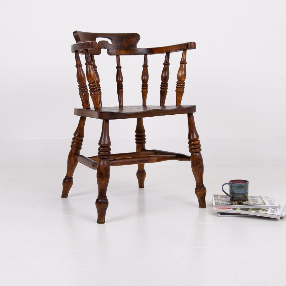 An antique 19th-century wooden smokers bow armchair with turned spindles, a curved horseshoe armrest, and a shaped seat. View II