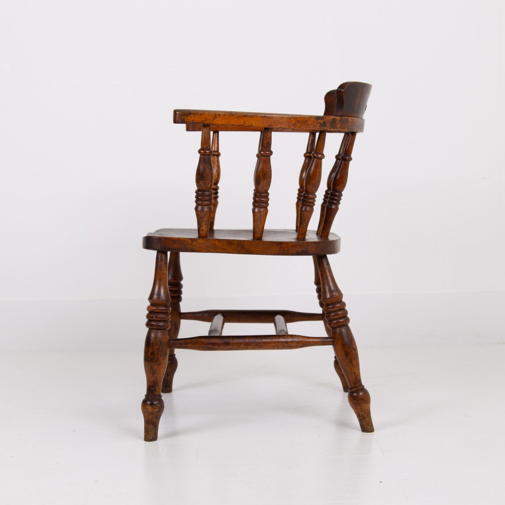 An antique 19th-century wooden smokers bow armchair with turned spindles, a curved horseshoe armrest, and a shaped seat. View III