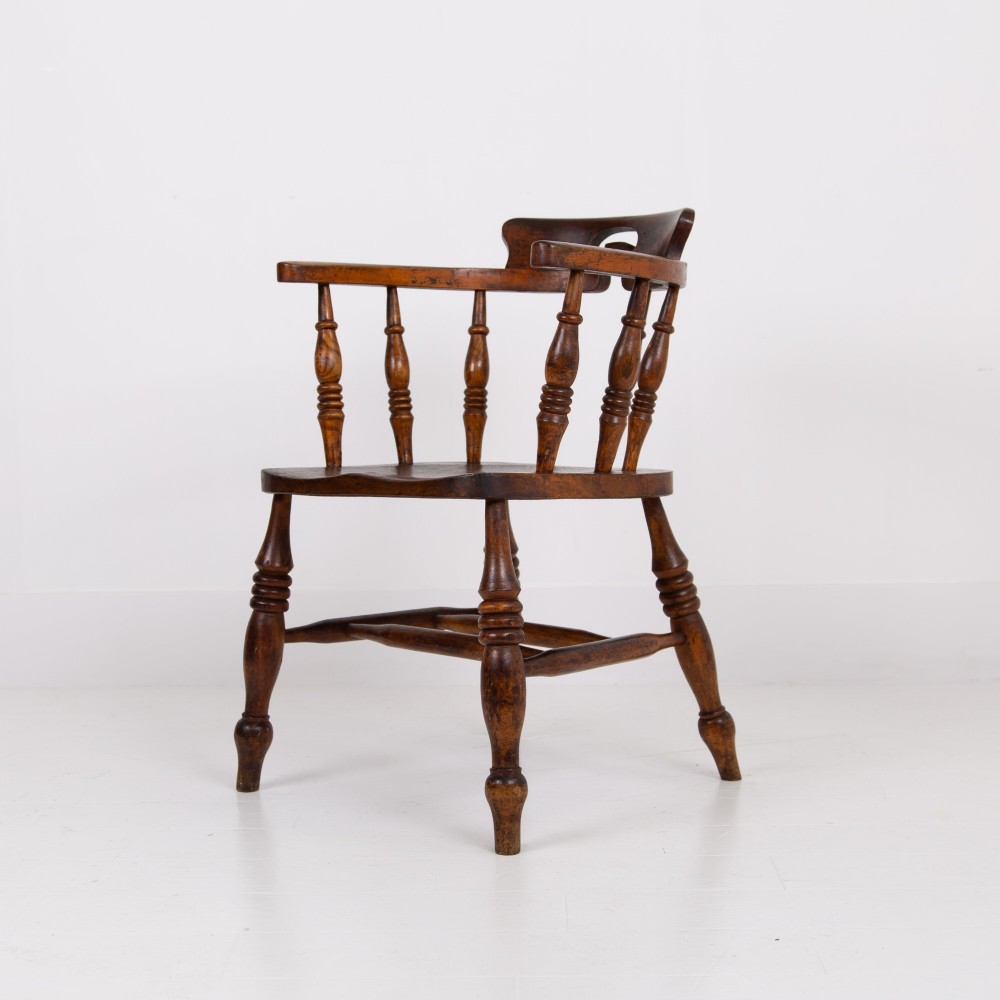 An antique 19th-century wooden smokers bow armchair with turned spindles, a curved horseshoe armrest, and a shaped seat. View IV