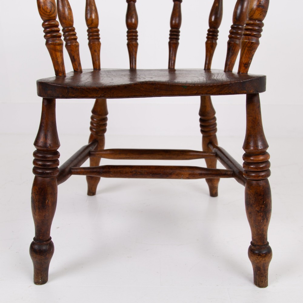 An antique 19th-century wooden smokers bow armchair with turned spindles, a curved horseshoe armrest, and a shaped seat. View VIII