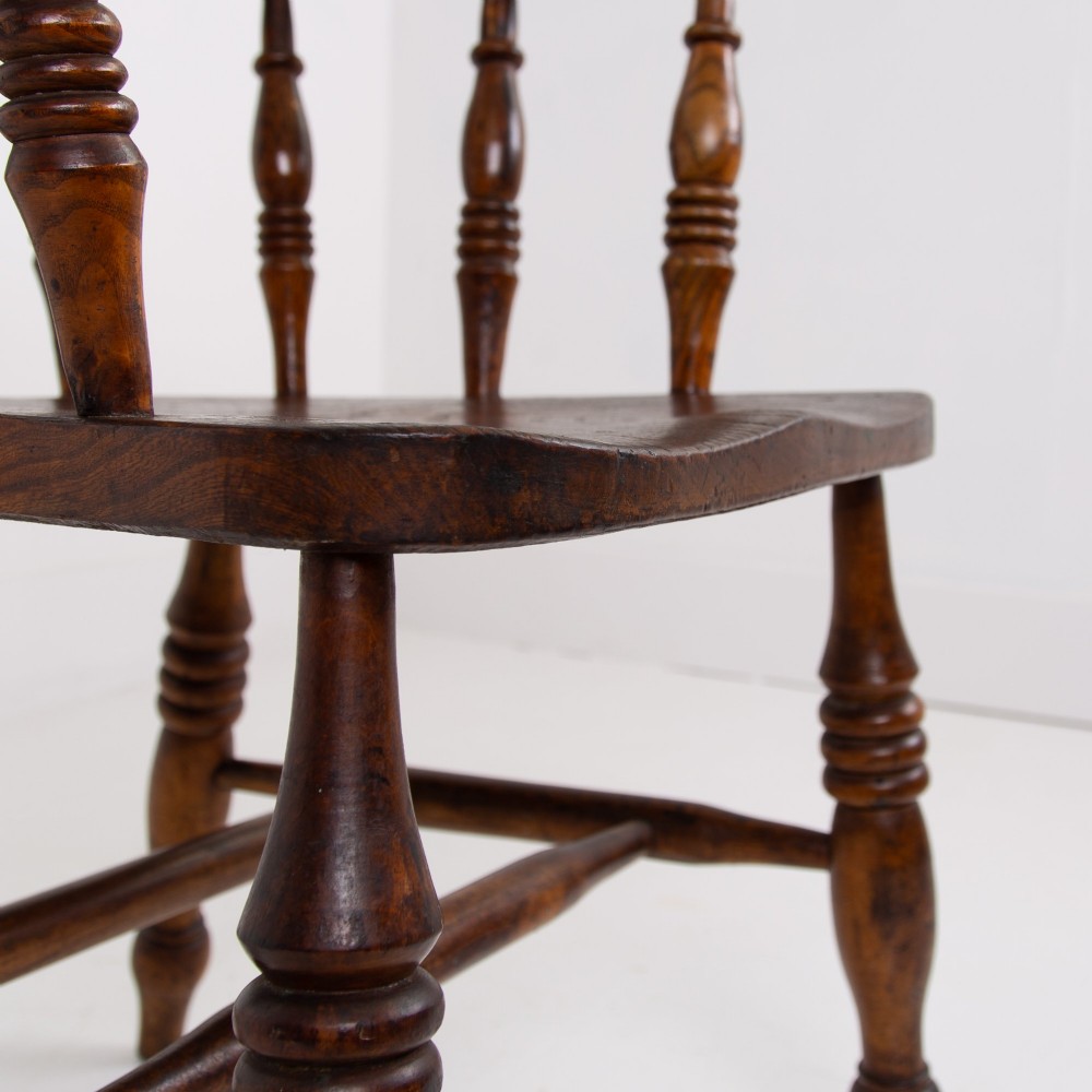An antique 19th-century wooden smokers bow armchair with turned spindles, a curved horseshoe armrest, and a shaped seat. View IX