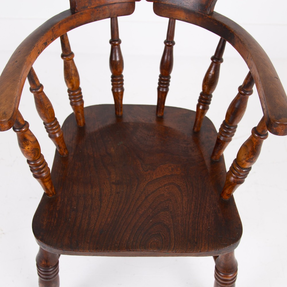 An antique 19th-century wooden smokers bow armchair with turned spindles, a curved horseshoe armrest, and a shaped seat. View X