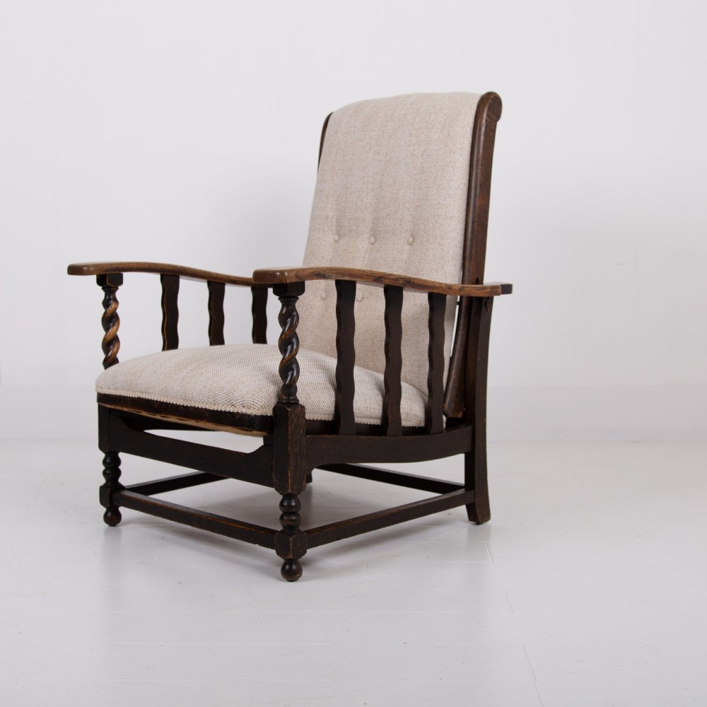 A pair of dark oak reclining armchairs with barley twist front supports, slatted sides, and beige textured upholstery. View V