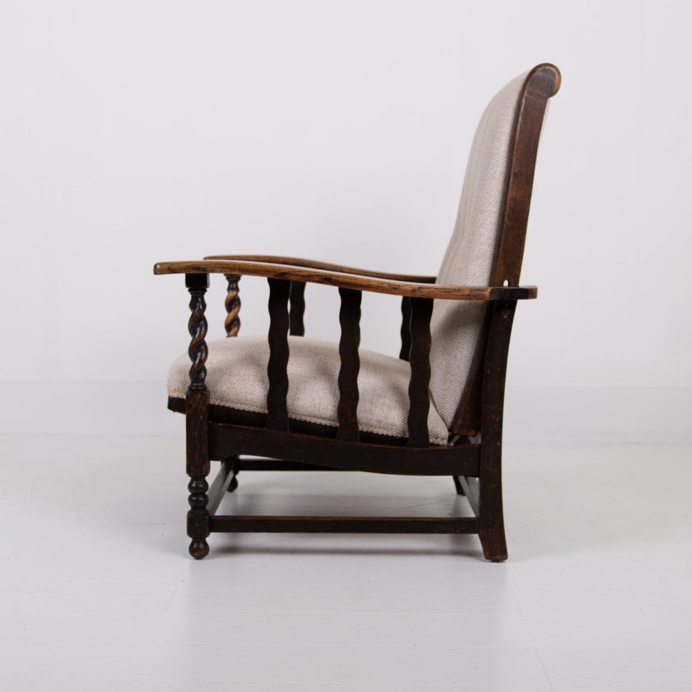 A pair of dark oak reclining armchairs with barley twist front supports, slatted sides, and beige textured upholstery. View VII