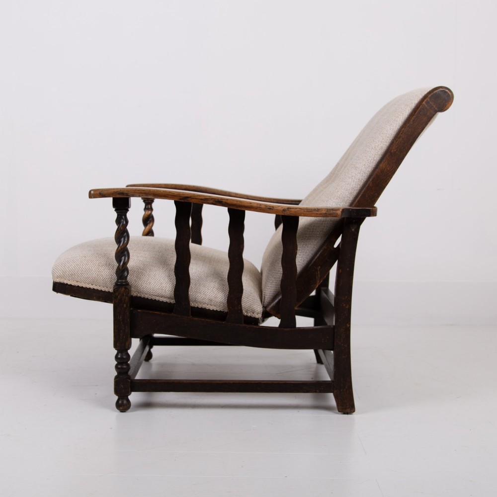 A pair of dark oak reclining armchairs with barley twist front supports, slatted sides, and beige textured upholstery. View VIII