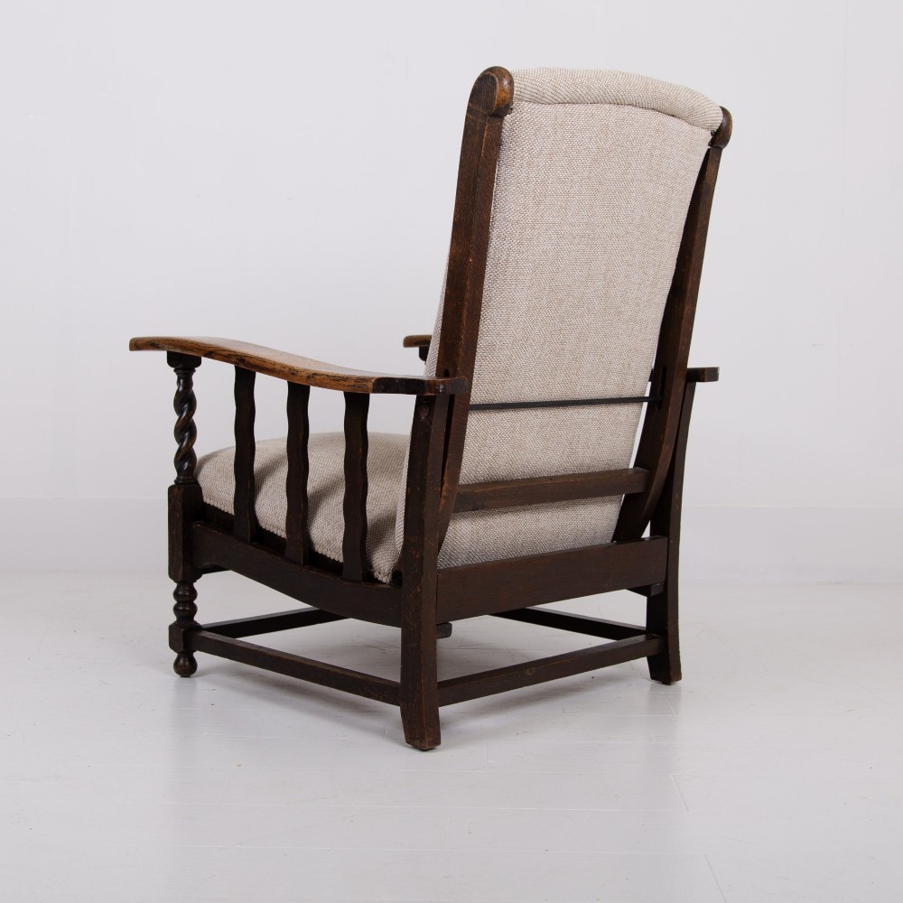 A pair of dark oak reclining armchairs with barley twist front supports, slatted sides, and beige textured upholstery. View IX