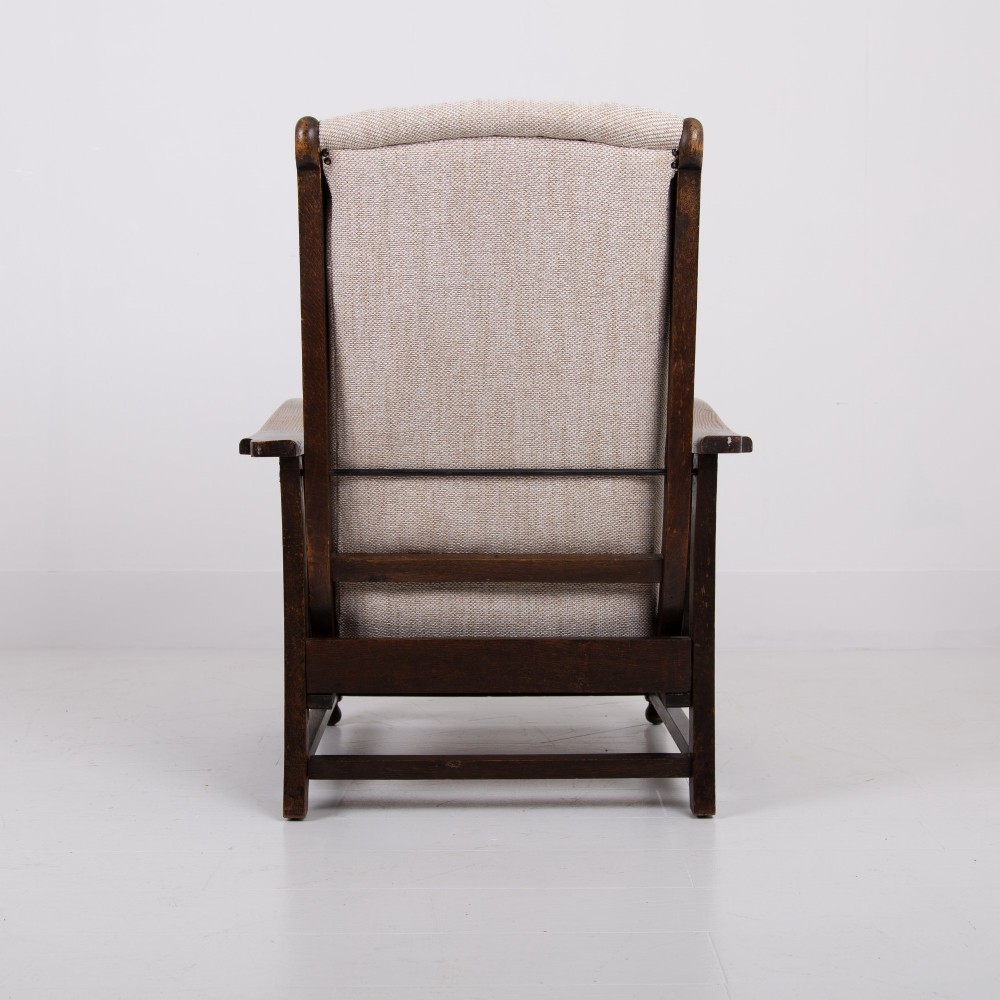 A pair of dark oak reclining armchairs with barley twist front supports, slatted sides, and beige textured upholstery. View X