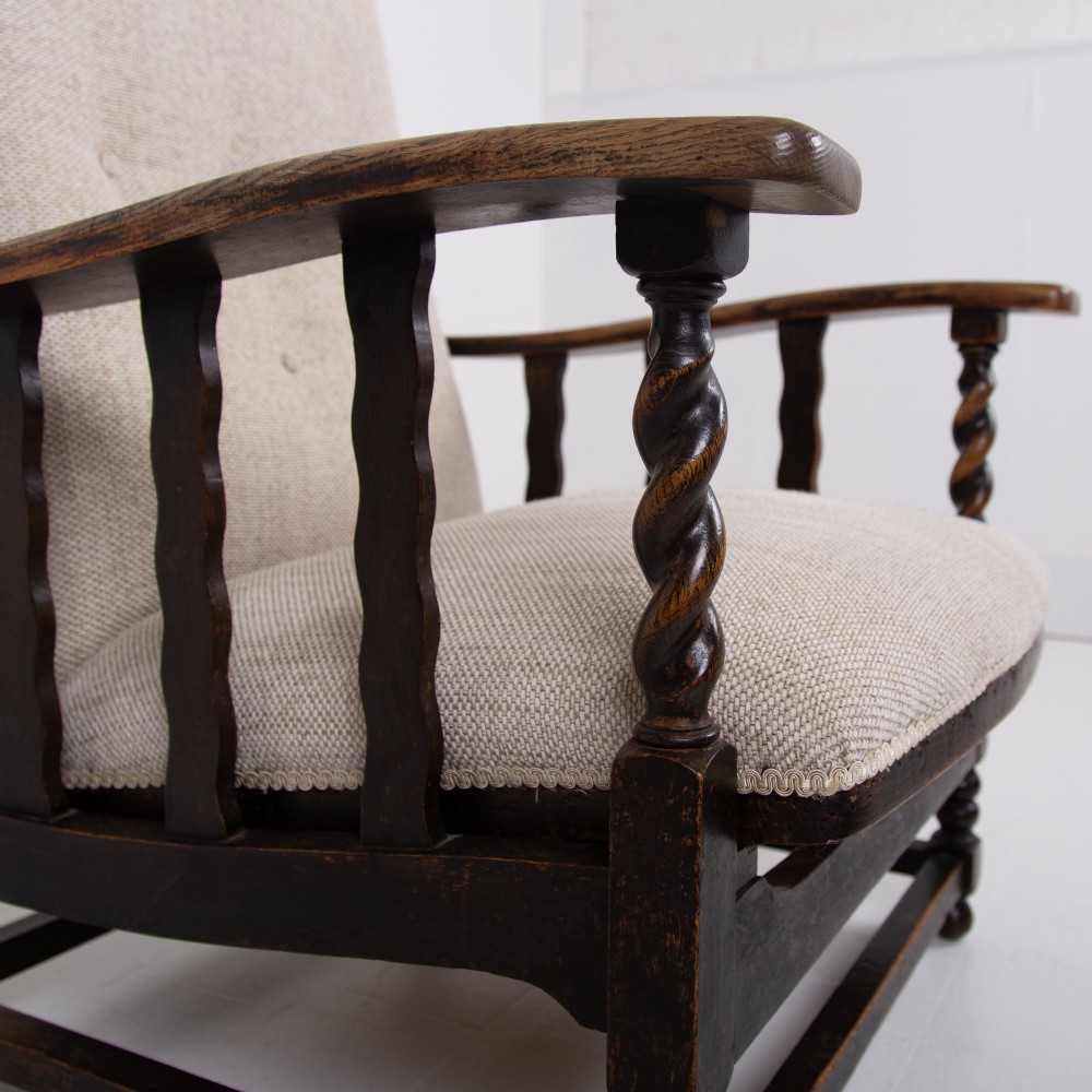 A pair of dark oak reclining armchairs with barley twist front supports, slatted sides, and beige textured upholstery. View XV