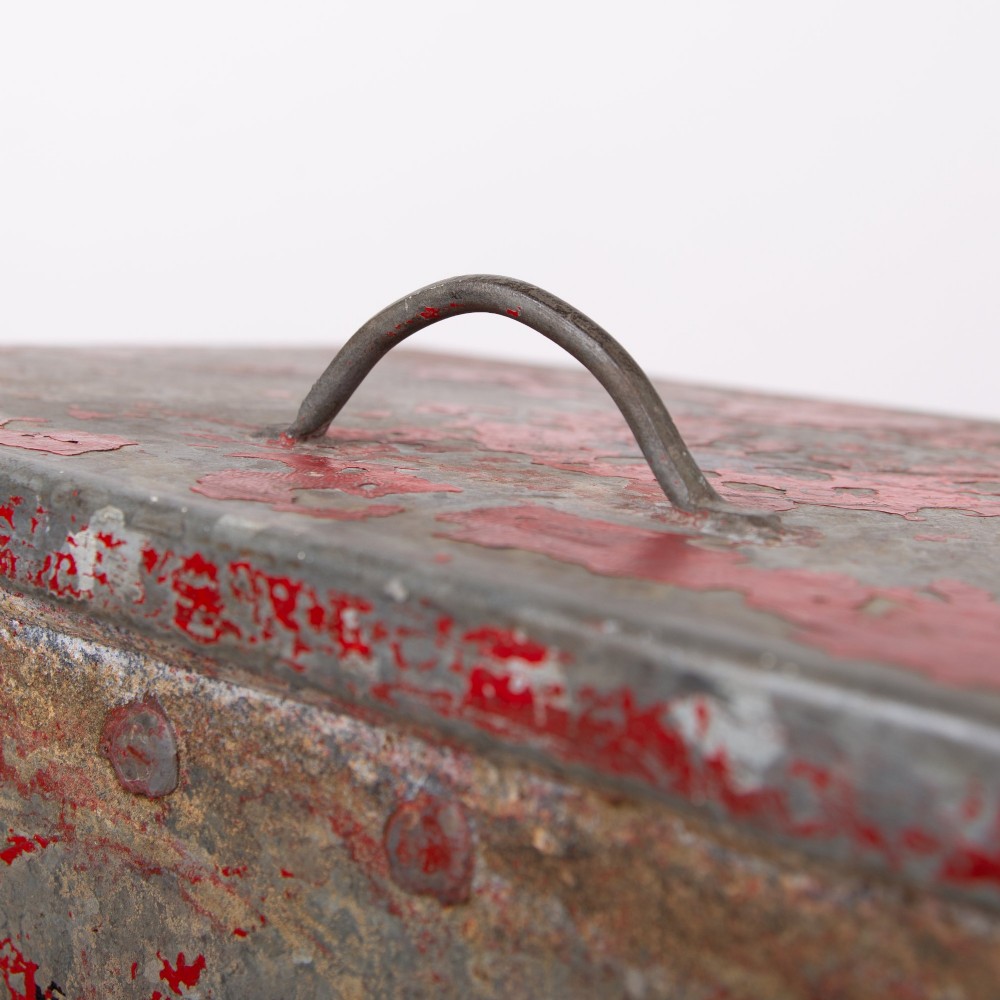 A tall rectangular industrial metal fire bin with distressed red paint, stencilled black text, a top lid, and four small cast iron swivel castors. View IX