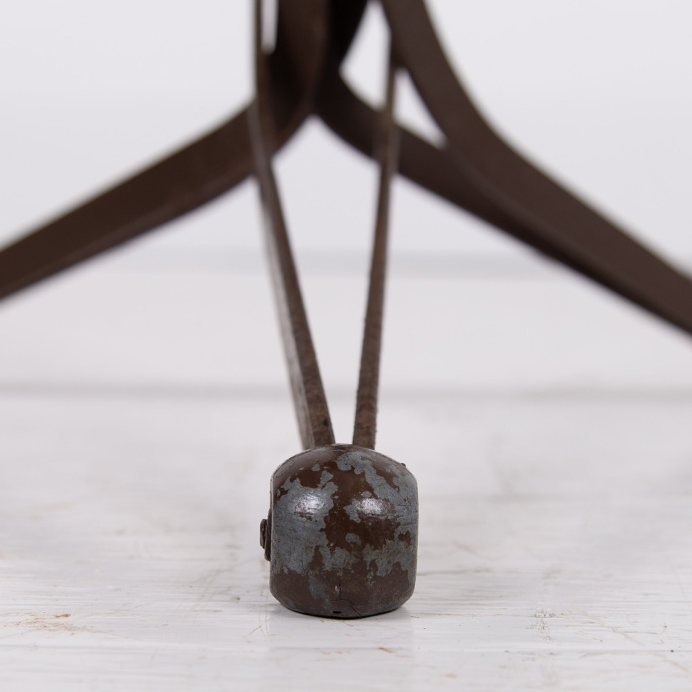 An industrial 1930s workshop stool featuring a circular wooden seat mounted on a dark brown metal tripod base with a threaded height adjustment mechanism. View IV