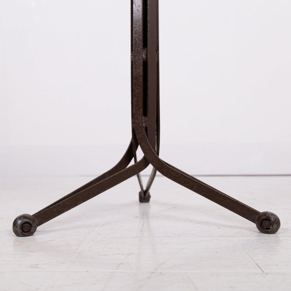 An industrial 1930s workshop stool featuring a circular wooden seat mounted on a dark brown metal tripod base with a threaded height adjustment mechanism. View V