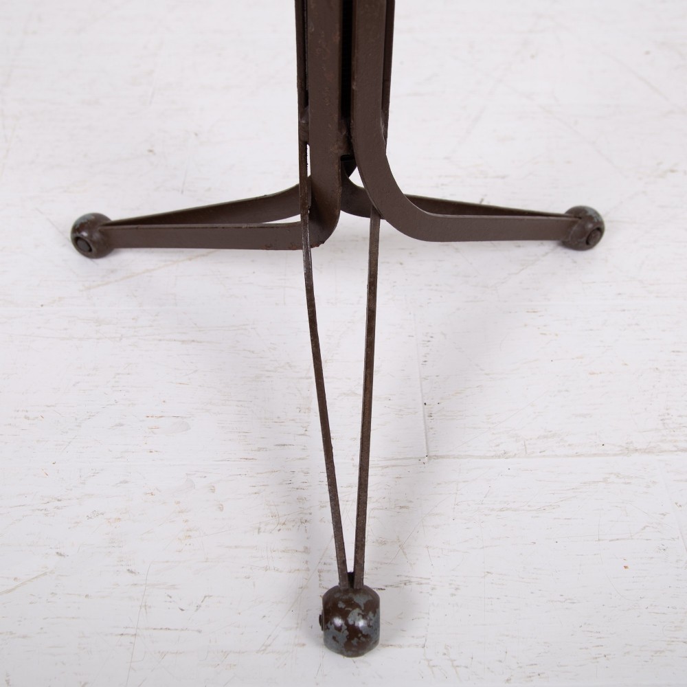 An industrial 1930s workshop stool featuring a circular wooden seat mounted on a dark brown metal tripod base with a threaded height adjustment mechanism. View X