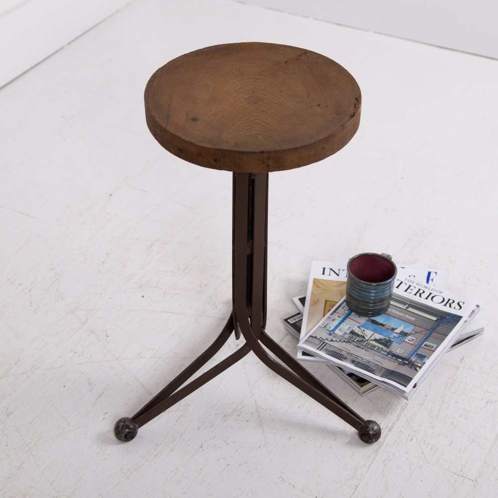 An industrial 1930s workshop stool featuring a circular wooden seat mounted on a dark brown metal tripod base with a threaded height adjustment mechanism. View XI