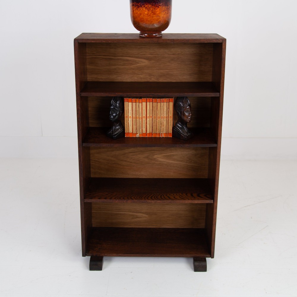 A 1930s open oak bookcase featuring four tier shelf sections and dark block feet against a plain background. View II