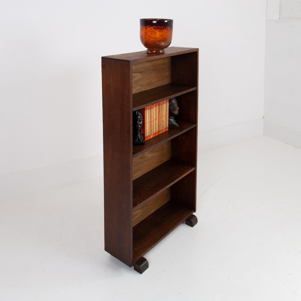 A 1930s open oak bookcase featuring four tier shelf sections and dark block feet against a plain background. View III