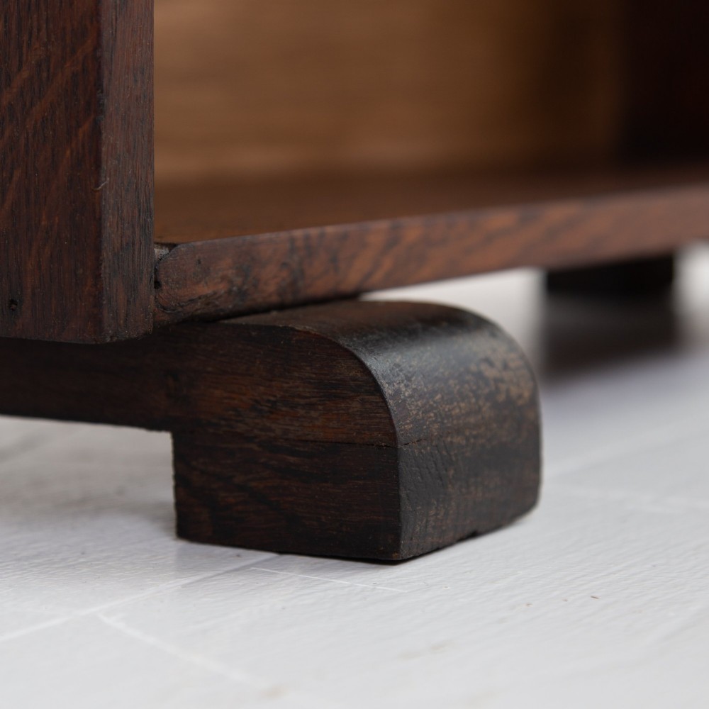 A 1930s open oak bookcase featuring four tier shelf sections and dark block feet against a plain background. View VI