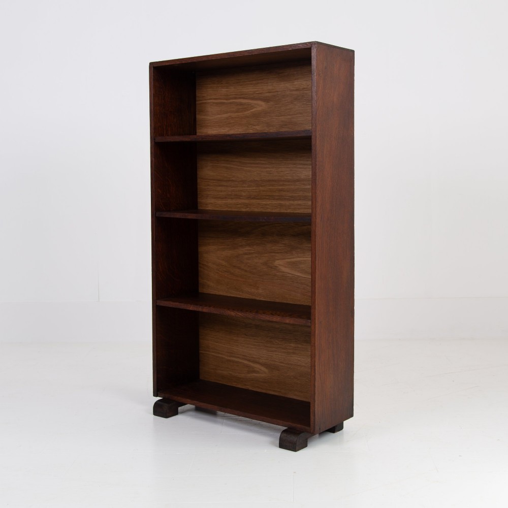 A 1930s open oak bookcase featuring four tier shelf sections and dark block feet against a plain background. View VII