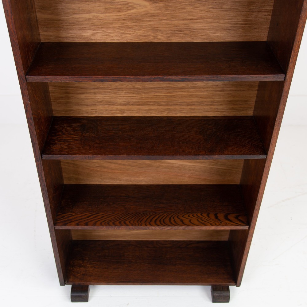 A 1930s open oak bookcase featuring four tier shelf sections and dark block feet against a plain background. View VIII