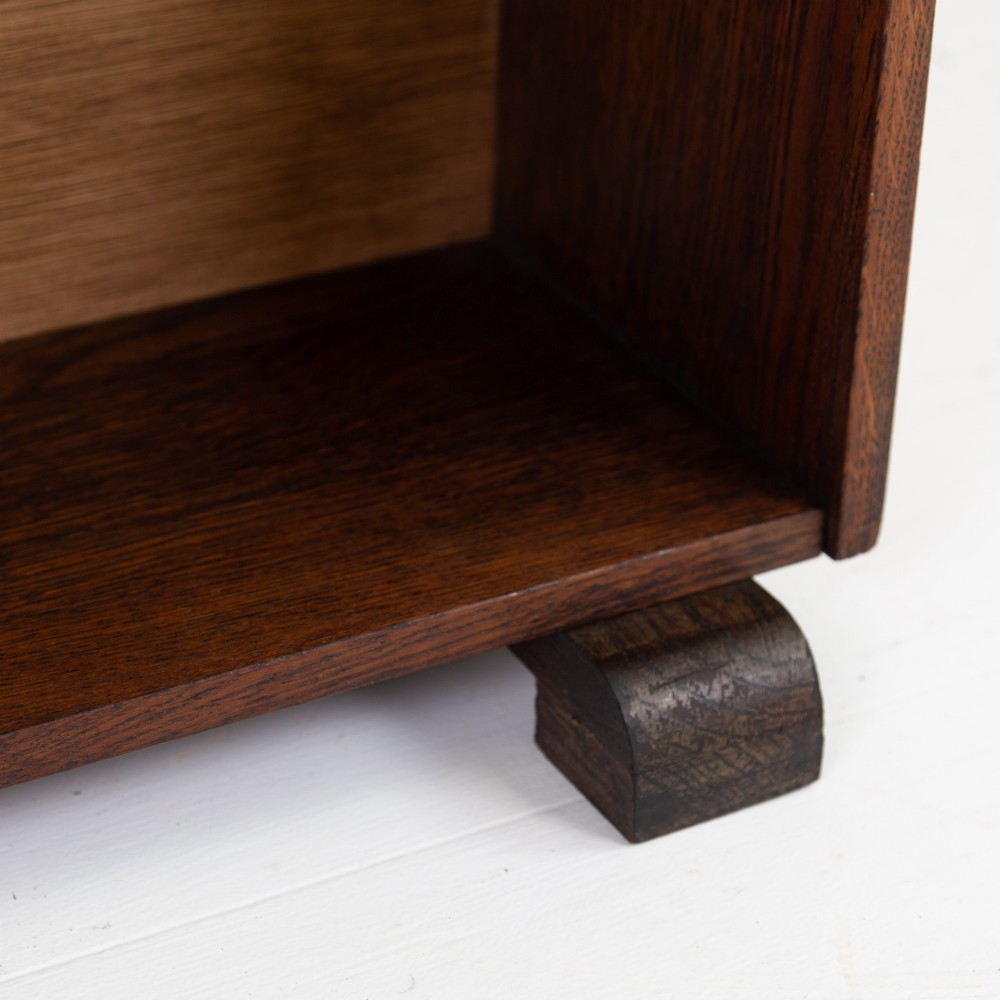 A 1930s open oak bookcase featuring four tier shelf sections and dark block feet against a plain background. View IX