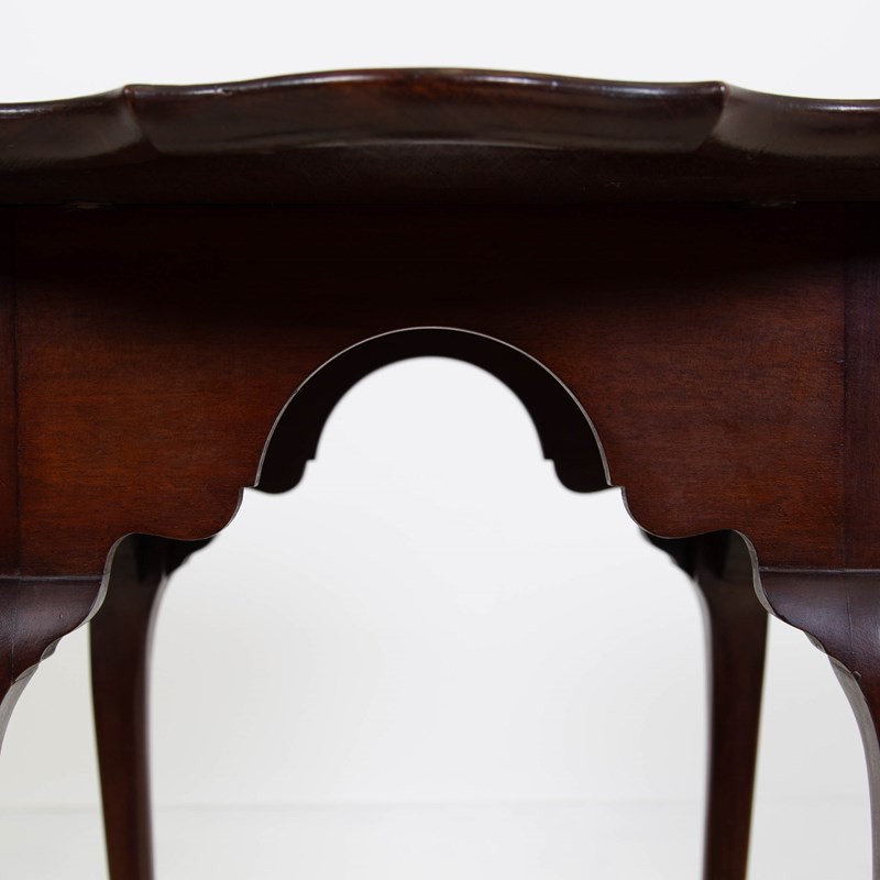 An antique dark mahogany side table featuring a scalloped piecrust top, arched aprons, slender cabriole legs with shell-carved knees, and a central circular lower tier. View VI