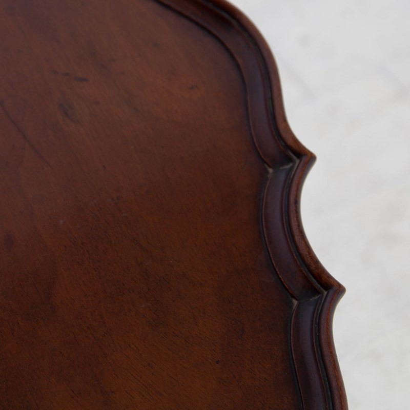 An antique dark mahogany side table featuring a scalloped piecrust top, arched aprons, slender cabriole legs with shell-carved knees, and a central circular lower tier. View VII