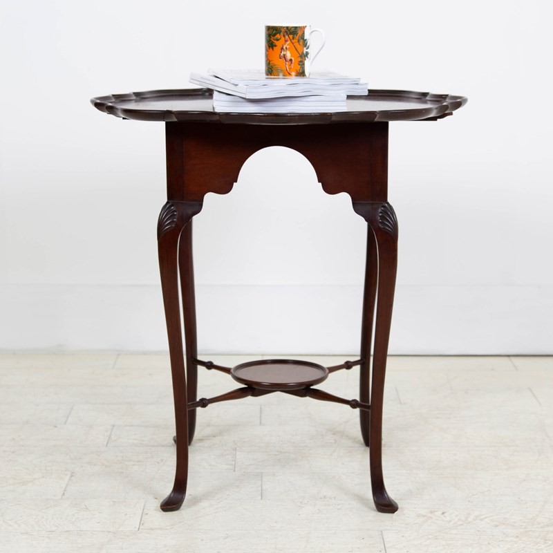 An antique dark mahogany side table featuring a scalloped piecrust top, arched aprons, slender cabriole legs with shell-carved knees, and a central circular lower tier. View VIII