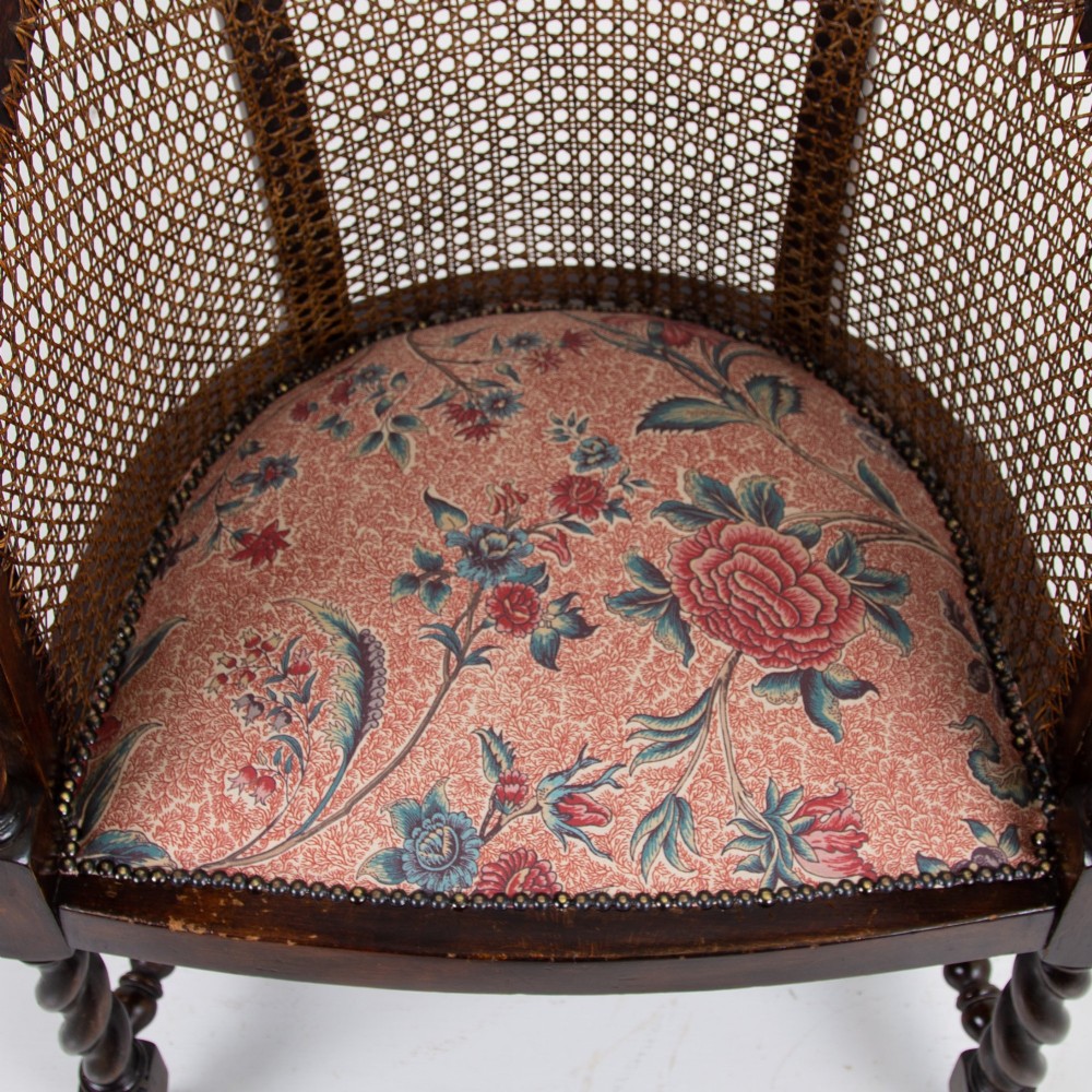 A dark wood Jacobean Revival tub armchair featuring woven cane panelling, carved barley twist legs, and a floral upholstered seat. View VII