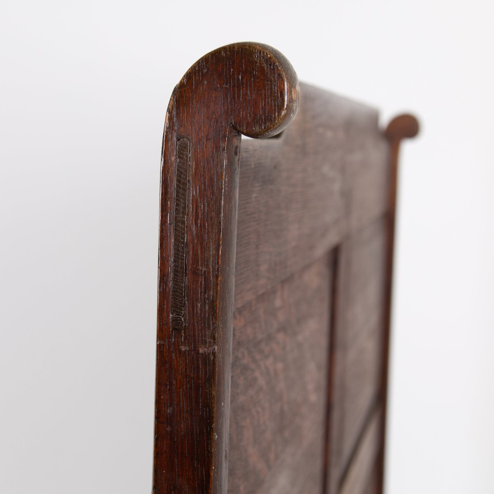 A 19th-century dark oak high-back box settle with panelled detailing, scrolled armrests, turned supports, and a hinged seat opening to a box storage base. View X