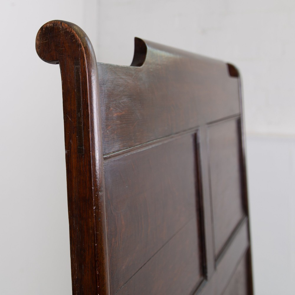 A 19th-century dark oak high-back box settle with panelled detailing, scrolled armrests, turned supports, and a hinged seat opening to a box storage base. View XIV
