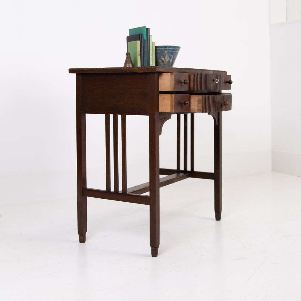 A 1930s Art Deco dark oak side table featuring six small drawers with fluted fronts and turned wooden handles, supported by tall legs and an H-stretcher. View II