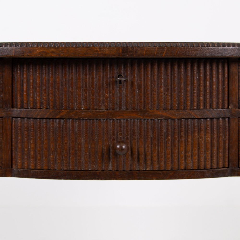 A 1930s Art Deco dark oak side table featuring six small drawers with fluted fronts and turned wooden handles, supported by tall legs and an H-stretcher. View VII