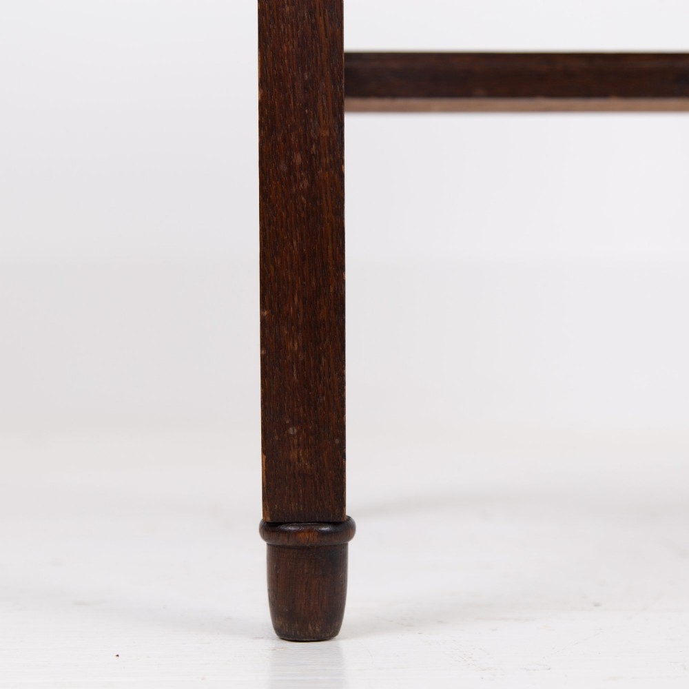 A 1930s Art Deco dark oak side table featuring six small drawers with fluted fronts and turned wooden handles, supported by tall legs and an H-stretcher. View IX