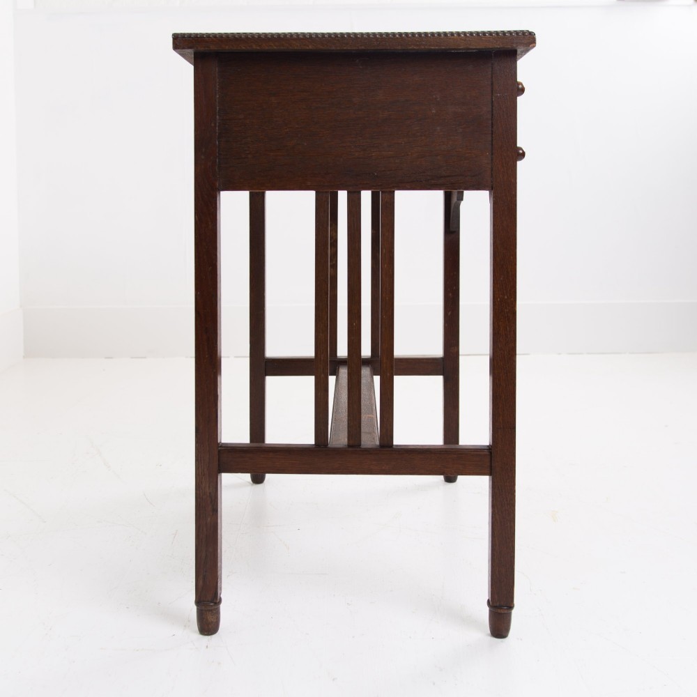 A 1930s Art Deco dark oak side table featuring six small drawers with fluted fronts and turned wooden handles, supported by tall legs and an H-stretcher. View X