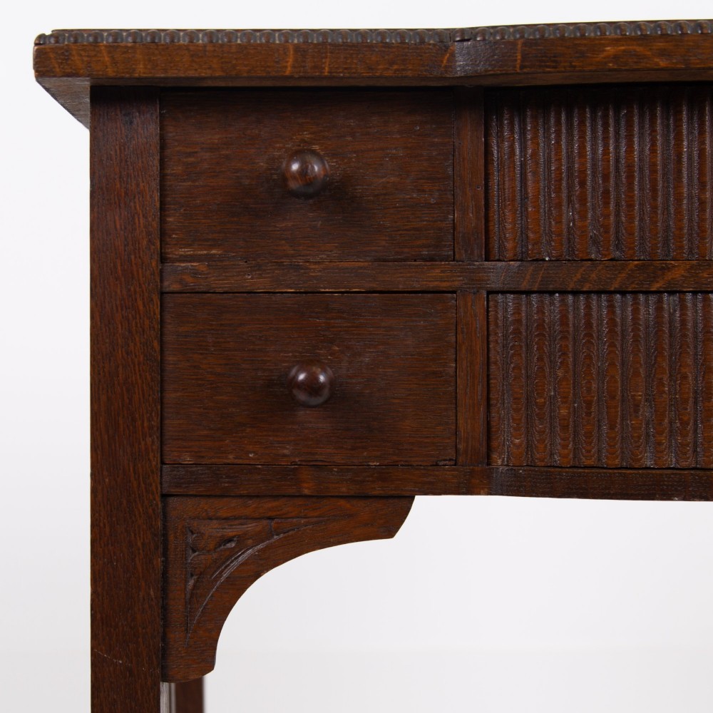 A 1930s Art Deco dark oak side table featuring six small drawers with fluted fronts and turned wooden handles, supported by tall legs and an H-stretcher. View XI