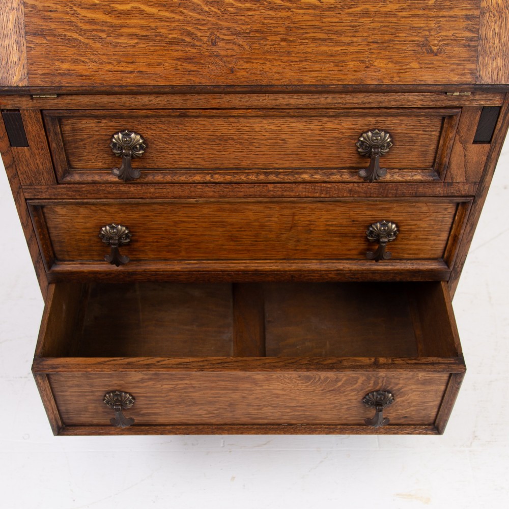 A small early 20th-century oak bureau bookcase featuring a leaded glass upper cabinet, a slant-front writing slope, and three lower drawers with brass drop handles. View XIII