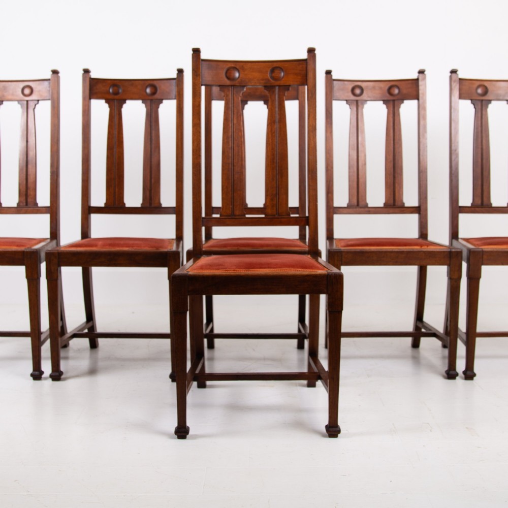 A set of six Scottish Arts and Crafts oak dining chairs featuring high slatted backs with carved roundel details and red velvet seat pads. View III
