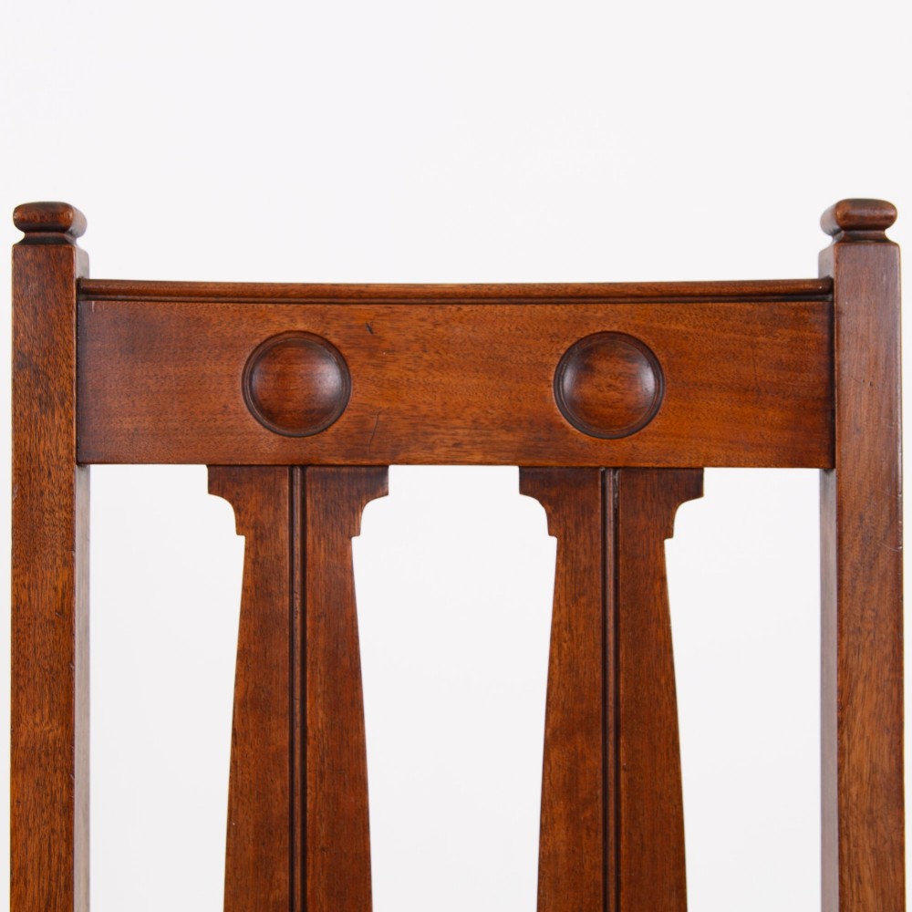 A set of six Scottish Arts and Crafts oak dining chairs featuring high slatted backs with carved roundel details and red velvet seat pads. View VII