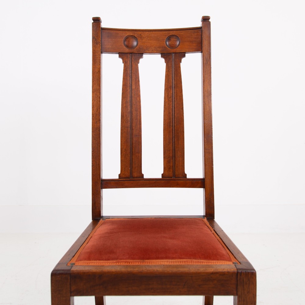 A set of six Scottish Arts and Crafts oak dining chairs featuring high slatted backs with carved roundel details and red velvet seat pads. View VIII