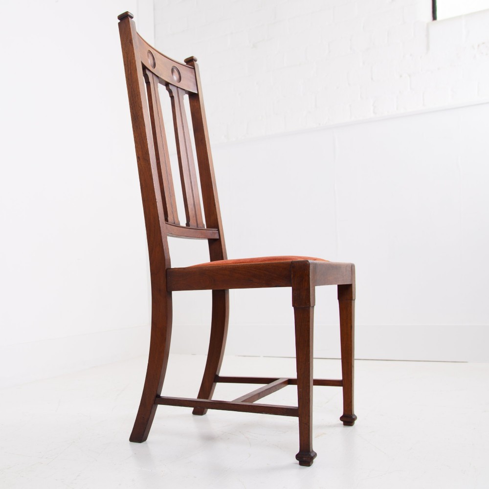 A set of six Scottish Arts and Crafts oak dining chairs featuring high slatted backs with carved roundel details and red velvet seat pads. View X