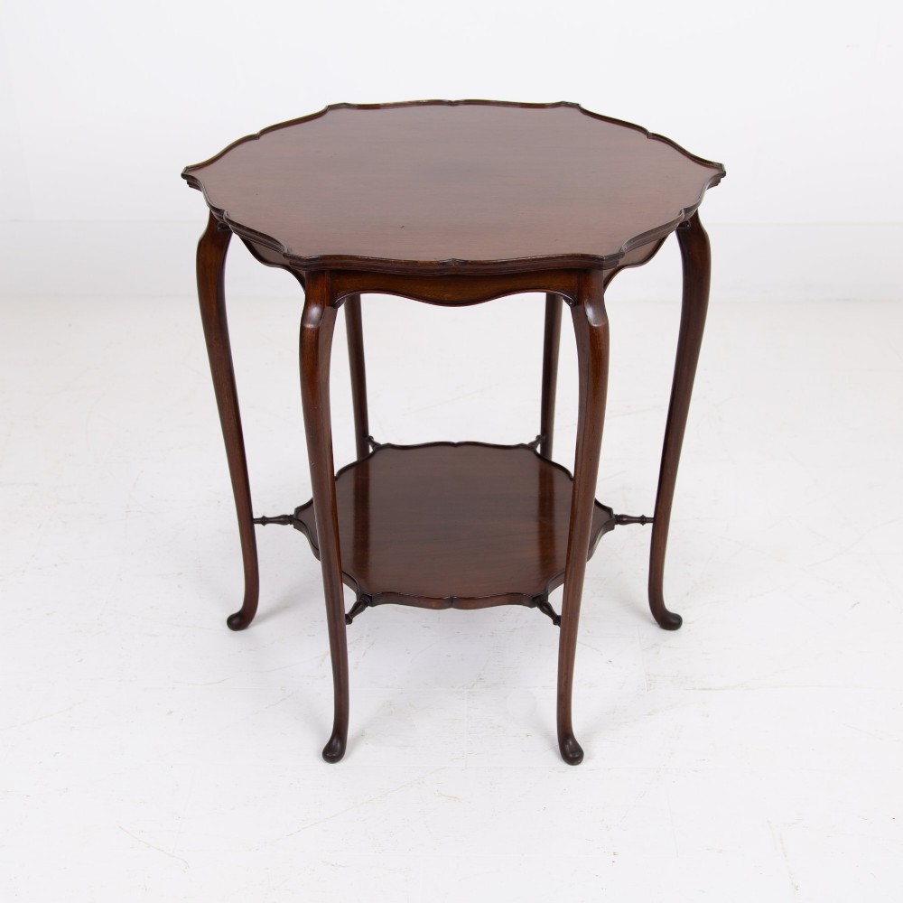 An Edwardian mahogany occasional side table featuring a scalloped rim top, slender cabriole legs, and a matching lower undertier shelf.