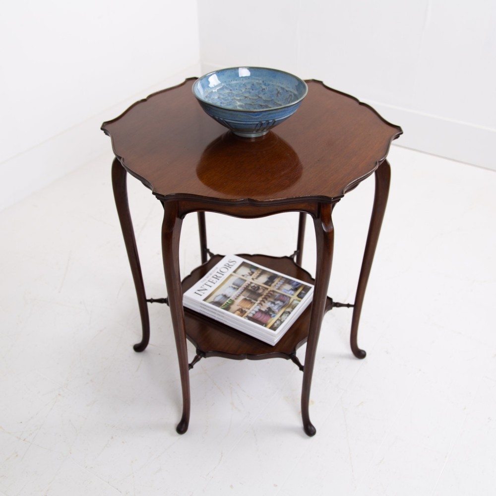 An Edwardian mahogany occasional side table featuring a scalloped rim top, slender cabriole legs, and a matching lower undertier shelf. View II