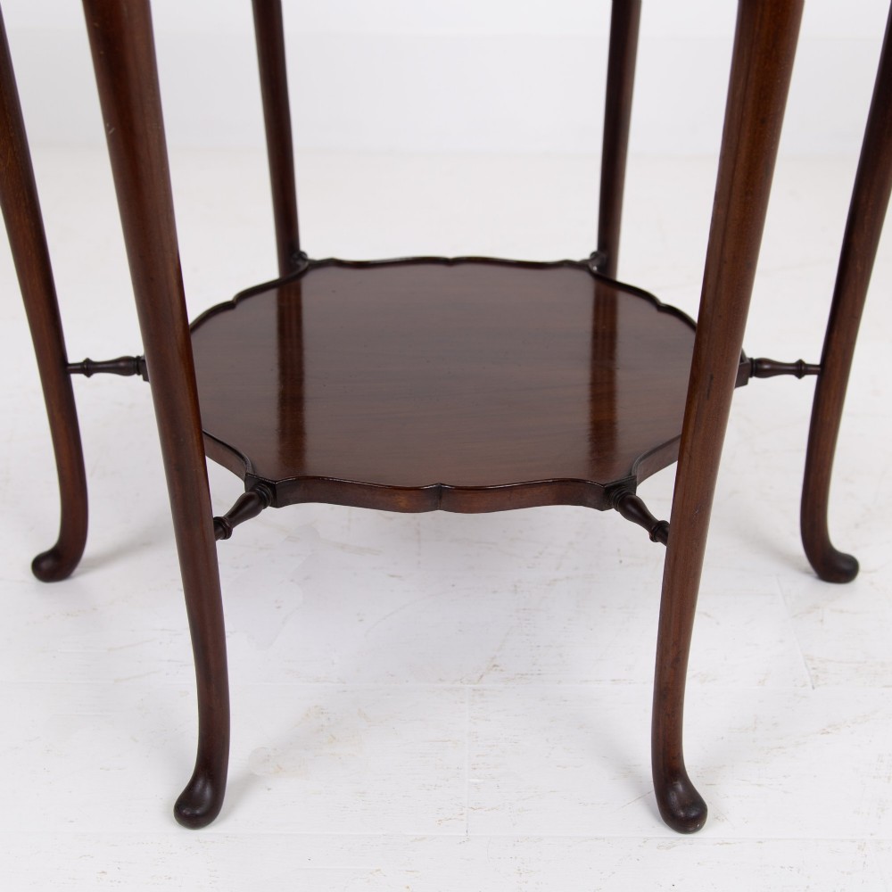 An Edwardian mahogany occasional side table featuring a scalloped rim top, slender cabriole legs, and a matching lower undertier shelf. View IV