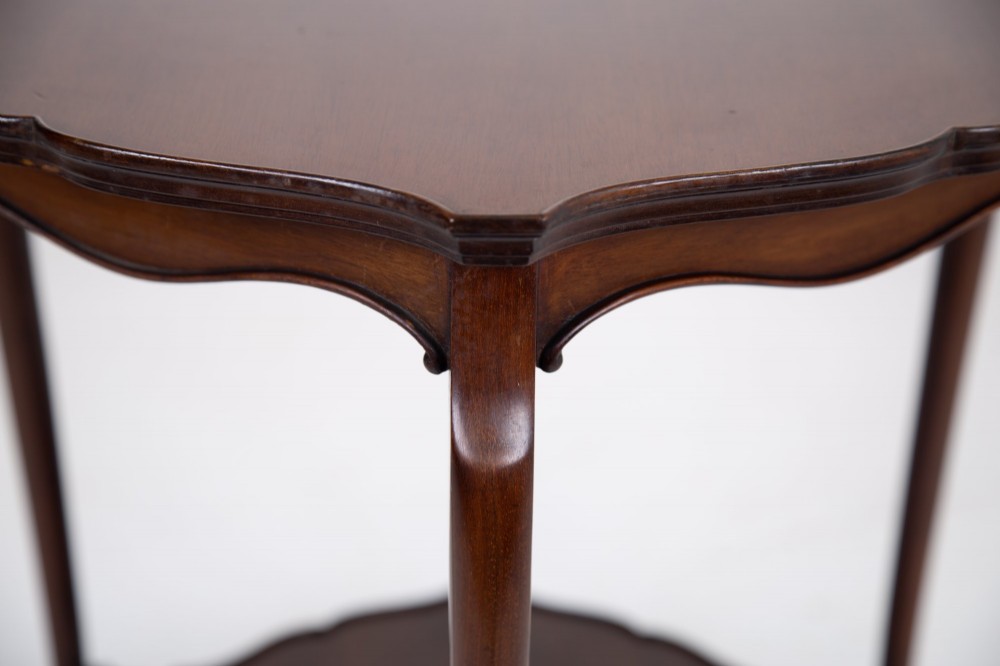 An Edwardian mahogany occasional side table featuring a scalloped rim top, slender cabriole legs, and a matching lower undertier shelf. View IX