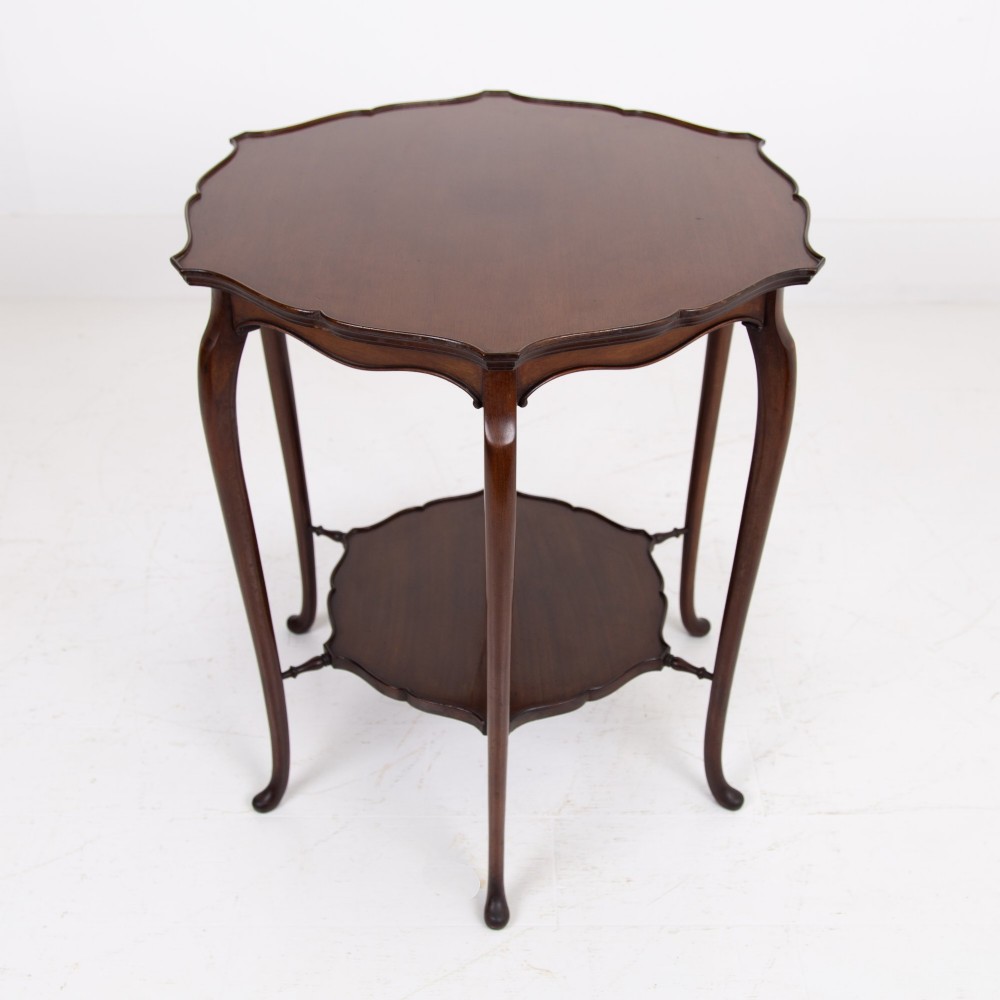 An Edwardian mahogany occasional side table featuring a scalloped rim top, slender cabriole legs, and a matching lower undertier shelf. View XI